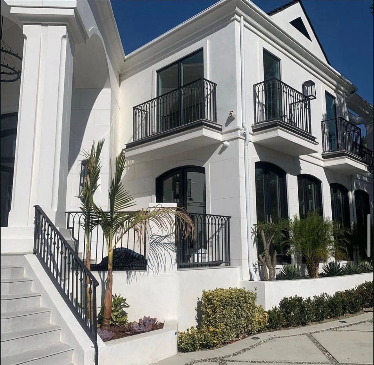 Black balcony railings and an entry stair railing on a white townhouse