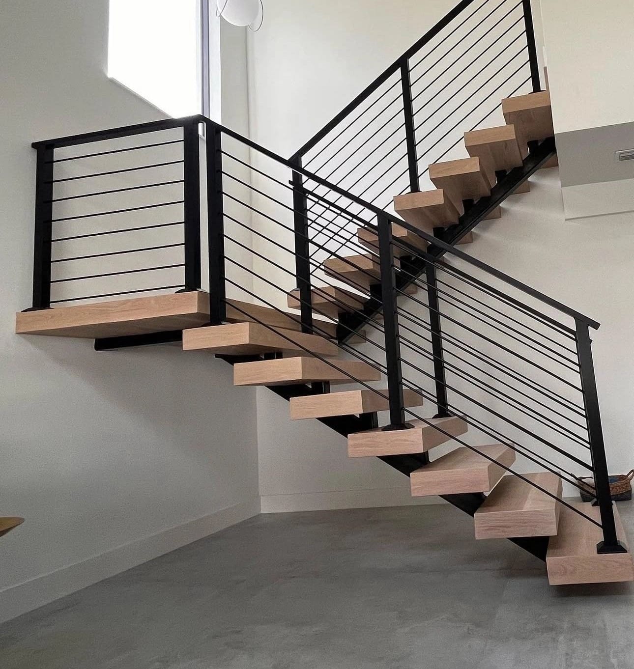 Floating staircase with wood treads and a black horizontal-bar railing